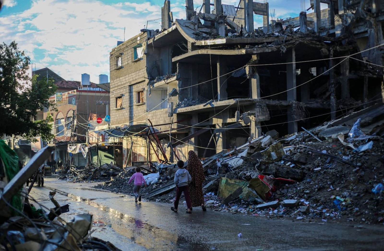 Women and children walking past destroyed buildings in Gaza