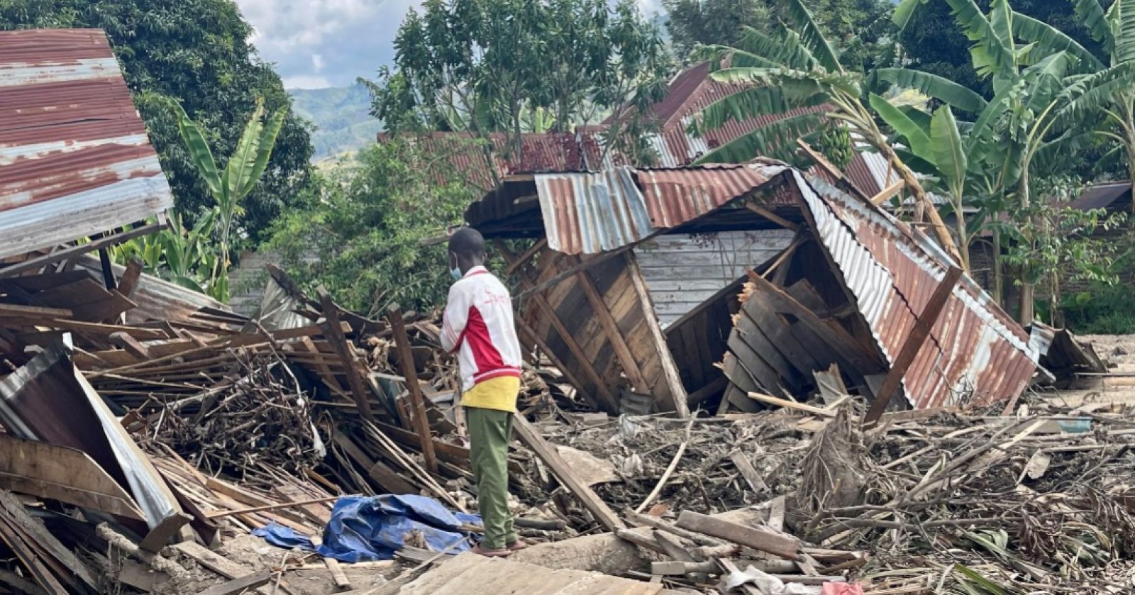 Boy standing in front of destroyed house
